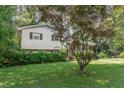 A split-level home with white siding and a manicured lawn, partially shaded by a mature maple tree at 612 Locust Ln, Raleigh, NC 27603
