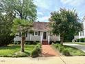 Inviting home with brick walkway, lush greenery, and mature trees at 120 W Front St, Oxford, NC 27565
