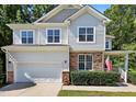 Attractive two-story home with stone accents, white siding, well-manicured landscaping, and an attached two-car garage at 1437 Lindenberg Sq, Wake Forest, NC 27587