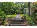 Inviting walkway leading to a modern home, surrounded by lush greenery and mature trees at 1908 S Lakeshore Dr, Chapel Hill, NC 27514