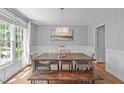 Sunlit dining room with hardwood floors, wainscoting, modern chandelier, and elegant decor provides a comfortable setting at 208 Silk Hope Dr, Cary, NC 27519