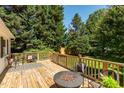 Outdoor deck with wood flooring, a cozy fire pit with stone surround, and seating area for relaxing at 210 Peachtree St, Roxboro, NC 27573