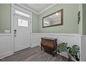 Inviting entryway with light green walls, white wainscoting, wood floors, and decorative accents at 22 Combine Trl, Benson, NC 27504
