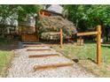 A gravel path and wood step lead to a home surrounded by manicured landscaping and mature trees at 28 Benchmark, Pittsboro, NC 27312