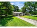 A comfortable single-story home featuring a covered carport and a long driveway, surrounded by greenery at 313 13Th St, Butner, NC 27509