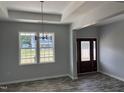 Inviting entryway featuring elegant chandelier, tray ceiling and wood-look flooring at 50 Leah Ln, Louisburg, NC 27549