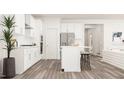 Open kitchen with white cabinets, island with seating, stainless appliances, and hardwood floors at 5553 Cayden Cove Dr, Wendell, NC 27591