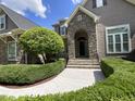 Stunning front entrance showcasing a stone archway, a well-manicured lawn, and stone walkway to front door at 1316 Plunket Dr, Wake Forest, NC 27587