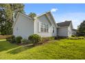 A view of the side of the light-colored home surrounded by a plush green lawn and bushes at 1401 Burchcrest Dr, Garner, NC 27529