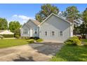 A view of the side of the light-colored home and the driveway with a large green lawn at 1401 Burchcrest Dr, Garner, NC 27529