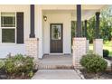 A close-up of the front porch with brick columns, a dark front door and tasteful landscaping at 454 Martins Mill Ct, Wendell, NC 27591