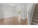Bright living room with hardwood floors, a window overlooking the lawn, and staircase at 4716 Miller Dr, Durham, NC 27704