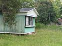 Side exterior view of a single-story home with faded green siding and overgrown grass at 000 Us Route One, Cameron, NC 28326