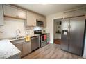 Modern kitchen featuring stainless steel appliances, grey cabinets, granite counters and wood-look flooring at 1206 Downing Rd, Raleigh, NC 27610