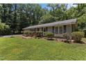 View of the front exterior, featuring a well-kept lawn, brick pathway, and ample foliage and large shade trees at 18 Red Pine Rd, Chapel Hill, NC 27516