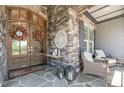 Inviting front porch featuring stone accents, seating, and decorative wreaths on the front door at 2112 Colin Hill Ct, Wake Forest, NC 27587