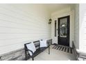 Inviting front porch with a bench, decorative pillows, and a welcoming wreath on the front door at 237 Emory Bluffs Dr, Holly Springs, NC 27540