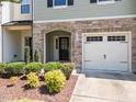 Welcoming front entry with stone archway, manicured landscaping, and attached garage at 3810 Prince Noah Loop, Wake Forest, NC 27587