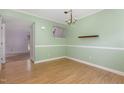 Bright dining room featuring a chandelier, light green walls, wood-look flooring, and a functional shelf at 4305 Lake Ridge Dr, Raleigh, NC 27604