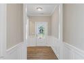 Inviting hallway with wood floors, white wainscoting, and a view of the front door at 705 Churton Pl, Cary, NC 27518