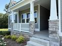 Front porch featuring stone pillars, gray siding and white railings adding curb appeal to the home at 78 Mineral Springs Way, Benson, NC 27504