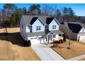 Aerial view of a two-story home with attached garage, manicured lawn, and wooded backdrop at 78 N Porcenna Ln, Clayton, NC 27527