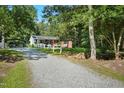 A quaint home sits surrounded by lush trees and a long gravel drive leading to a carport at 904 Lanier Farm Rd, Sanford, NC 27330