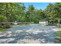 Wide shot of a gravel yard, shadowed by trees, with a carport and fenced-off section at 904 Lanier Farm Rd, Sanford, NC 27330