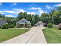 Beautiful home with a long driveway, a detached garage, green lawn, and a serene wooded backdrop at 101 Ferndale Ct, Clayton, NC 27520