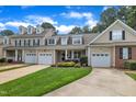 A beige townhome features an attached garage, a front lawn, and a driveway at 1326 Fairview Club Dr, Wake Forest, NC 27587