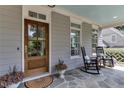 Cozy front porch features rocking chairs and stone flooring by a beautiful glass front door at 1830 Wilshire Ave, Raleigh, NC 27608