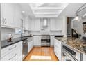 Bright kitchen featuring white cabinets, a skylight, stainless steel appliances, and hardwood flooring at 2816 Keck Dr, Burlington, NC 27215
