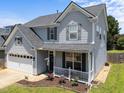 Inviting exterior showcasing a cozy porch, two-car garage, and freshly landscaped front garden at 300 Stobhill Ln, Holly Springs, NC 27540