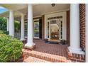 Inviting covered porch with brick flooring, white columns, and a clear view of the home's entry at 315 Birdwood Ct, Cary, NC 27519