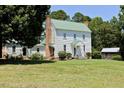 Side view of house with green roof, mature trees, brick chimneys, and outbuilding at 4822 Nc Highway 98 W, Youngsville, NC 27596