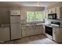 Functional kitchen features white cabinets, countertops, modern appliances and view of backyard at 501 Morgan Ter, Burlington, NC 27217