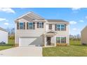 Two-story home featuring a front-facing garage, black shutters, and a landscaped lawn at 597 Leven Dr, Gibsonville, NC 27249