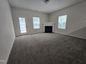 Spacious living room featuring a fireplace, carpet flooring, and a door to backyard at 6408 Bunker Hill Dr, Raleigh, NC 27610