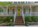 Close-up view of the home's entrance featuring a bright yellow door and brick stairs at 716 Beddingfield Dr, Knightdale, NC 27545