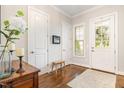 Bright foyer featuring hardwood floors, white trim, and a welcoming front door with sidelight at 1020 Regency Cottage Pl, Cary, NC 27518