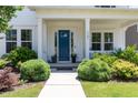 Close up shot of the entry with a blue front door, covered porch with rocking chairs, and manicured landscaping at 1502 Spring Overlook Ln, Hillsborough, NC 27278