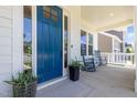 Inviting covered front porch with rocking chairs, beautiful blue door, and manicured landscaping at 1502 Spring Overlook Ln, Hillsborough, NC 27278