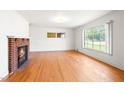 Bright living room with a brick fireplace and hardwood flooring at 1702 Pinecrest St, Burlington, NC 27215