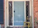 Inviting light blue front door with sidelights, door mat and decorative chair at 207 Wood Cir, Chapel Hill, NC 27514