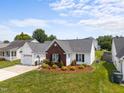 Well-maintained home showcasing brick accents, tidy landscaping, and an attached garage at 302 Slate Dr, Gibsonville, NC 27249