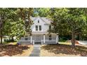 Charming two-story home with a inviting front porch and a classic design, surrounded by mature trees at 347 W Trade St, Burlington, NC 27217