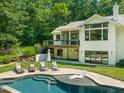 Beautiful backyard view with a large pool, stone patio, lounge seating, and lush greenery, ideal for relaxation and entertaining at 3707 Stonegate Dr, Chapel Hill, NC 27516