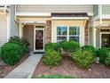 Charming townhome entrance with a decorative wreath, lush landscaping, and a welcoming walkway at 7809 Lillyhurst Dr, Raleigh, NC 27612