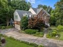 Back exterior view with garage, lush landscaping, and stone driveway at 102 Alidade Ct, Cary, NC 27513