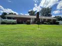 A brick home exterior view with a lush green lawn and partial fence against a partly cloudy sky at 1828 Fletchers Chapel Rd, Durham, NC 27703
